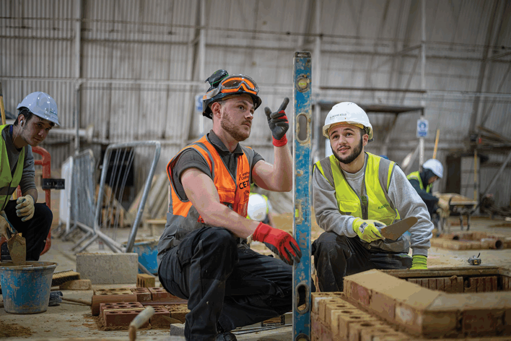 A qualified CETC instructor teaching a younger apprentice brick layer