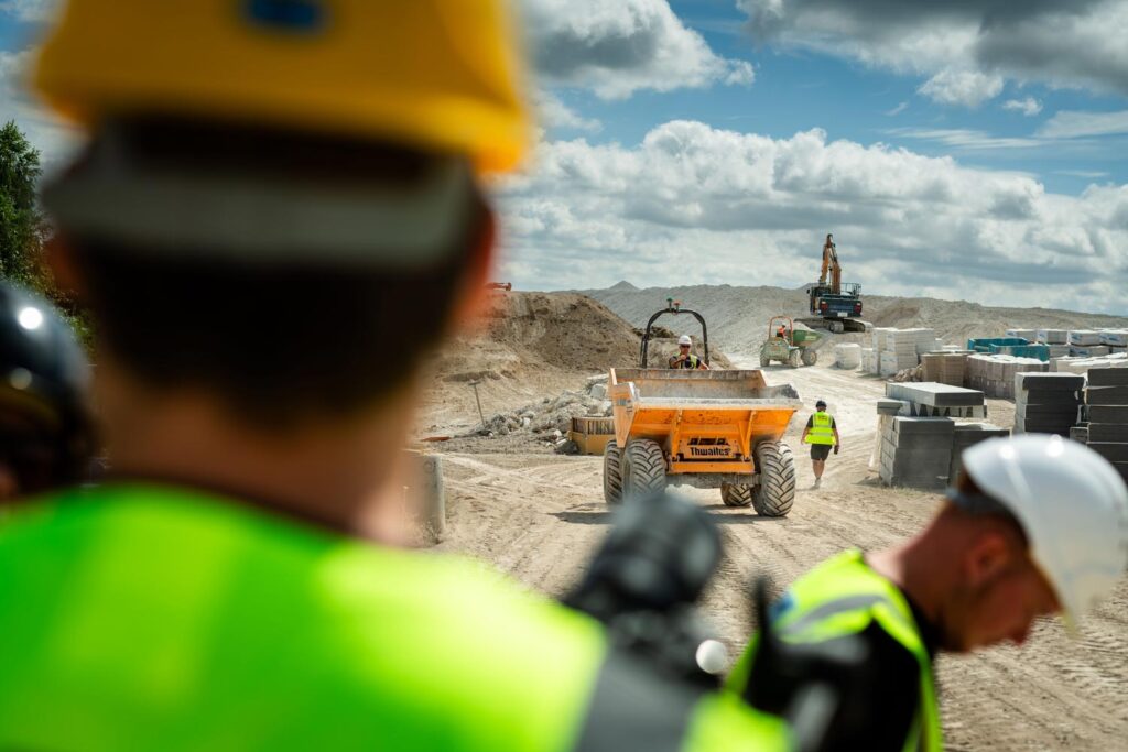 who we are, man standing, overlooking construction site wearing high vis and safety gear.